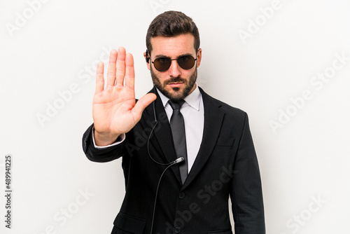 Canvas Print Young caucasian bodyguard man isolated on white background standing with outstretched hand showing stop sign, preventing you
