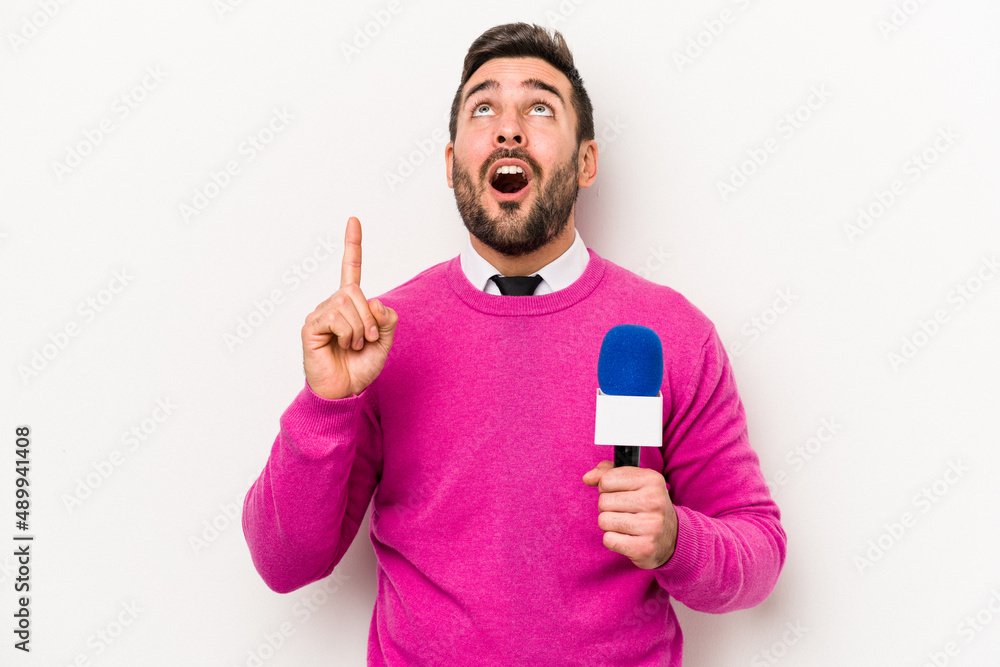 Young caucasian tv presenter man isolated on white background pointing upside with opened mouth. Young caucasian tv presenter man isolated on white background pointing upside with opened mouth.