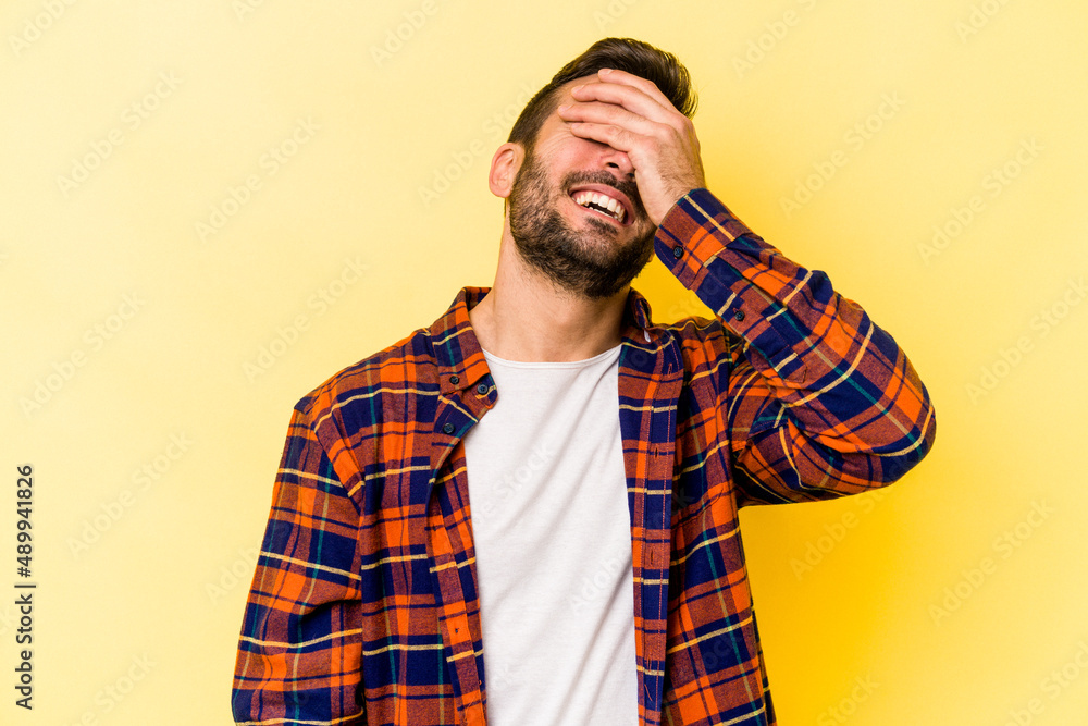 Young caucasian man isolated on yellow background laughs joyfully keeping hands on head. Happiness concept. Young caucasian man isolated on yellow background laughs joyfully keeping hands on head. Happiness concept.