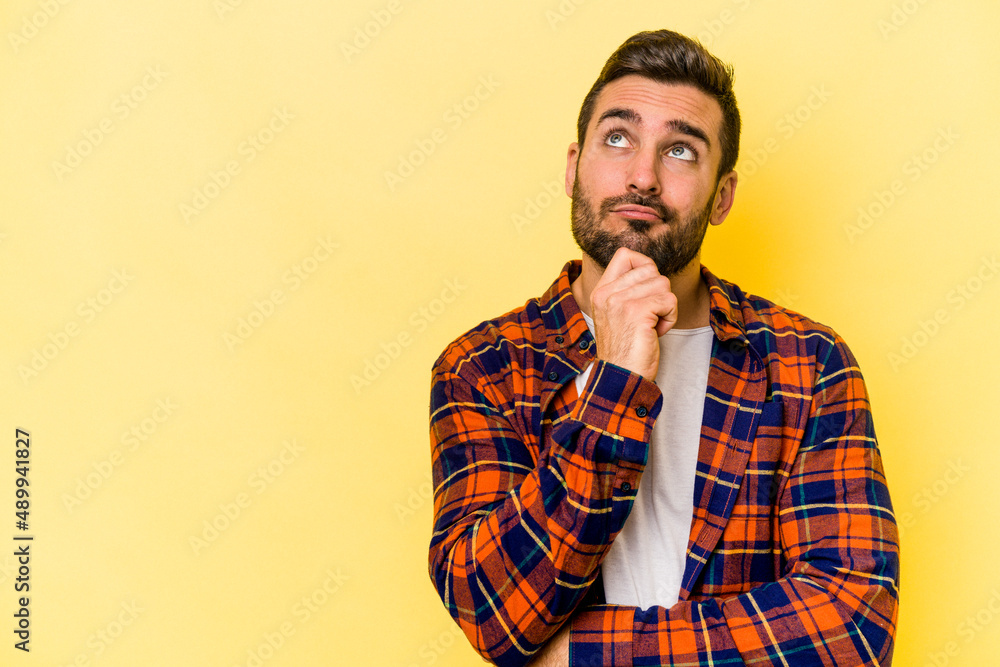 Young caucasian man isolated on yellow background looking sideways with doubtful and skeptical expression. Young caucasian man isolated on yellow background looking sideways with doubtful and skeptical expression.