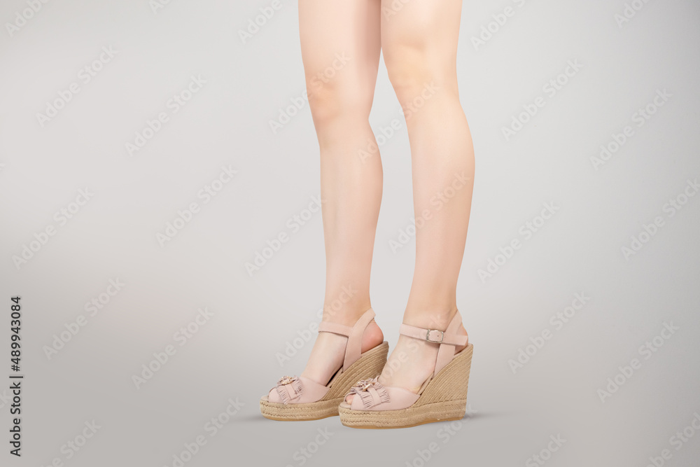 Studio shot of a young woman's legs in a pair of pink platform wedge shoes on grey background Studio shot of a young woman's legs in a pair of pink platform wedge shoes on grey background