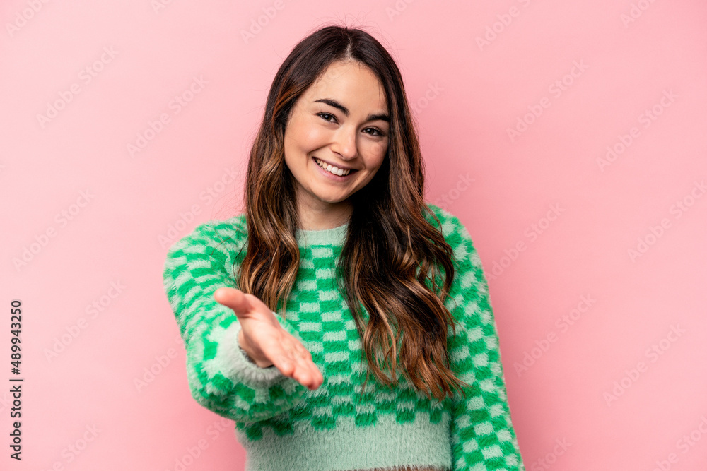 Young caucasian woman isolated on pink background stretching hand at camera in greeting gesture. Young caucasian woman isolated on pink background stretching hand at camera in greeting gesture.