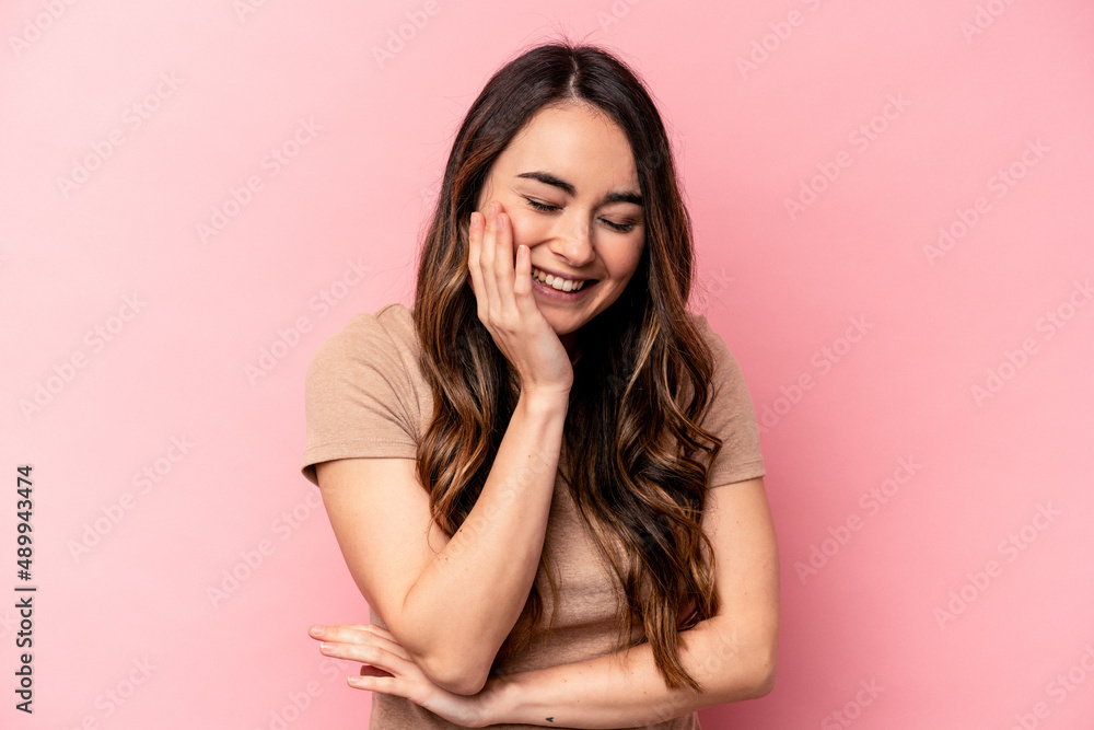 Young caucasian woman isolated on pink background laughs happily and has fun keeping hands on stomach. Young caucasian woman isolated on pink background laughs happily and has fun keeping hands on stomach.