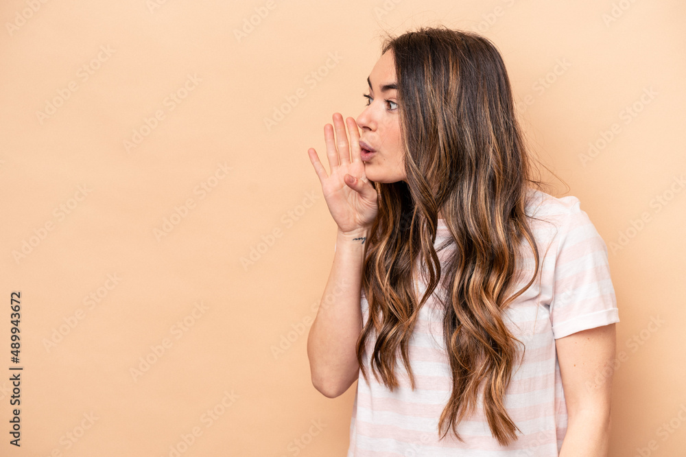 Young caucasian woman isolated on beige background is saying a secret hot braking news and looking aside Young caucasian woman isolated on beige background is saying a secret hot braking news and looking aside
