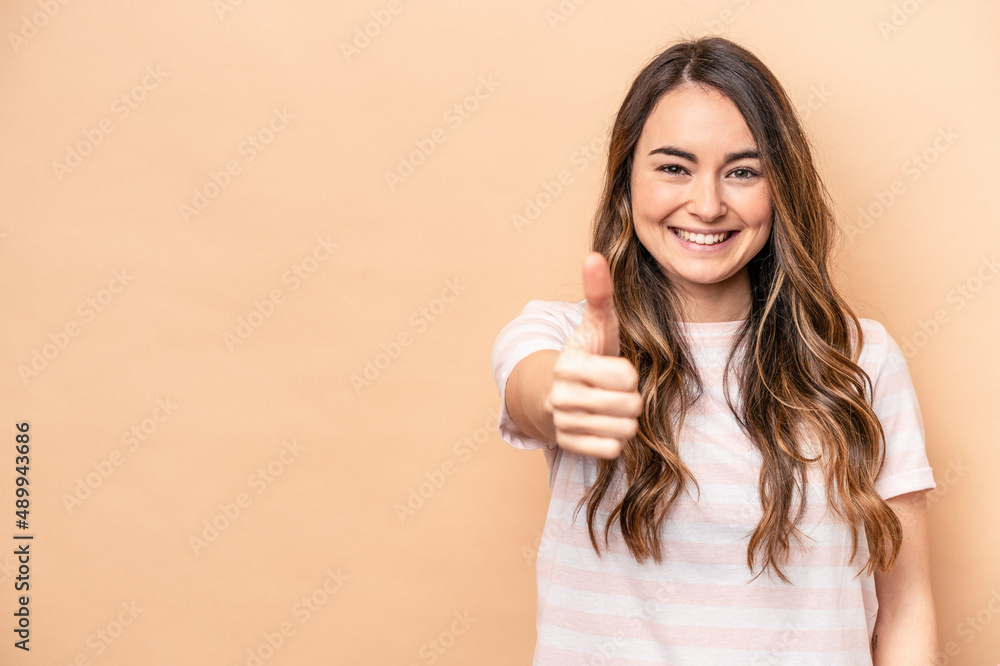 Young caucasian woman isolated on beige background smiling and raising thumb up Young caucasian woman isolated on beige background smiling and raising thumb up