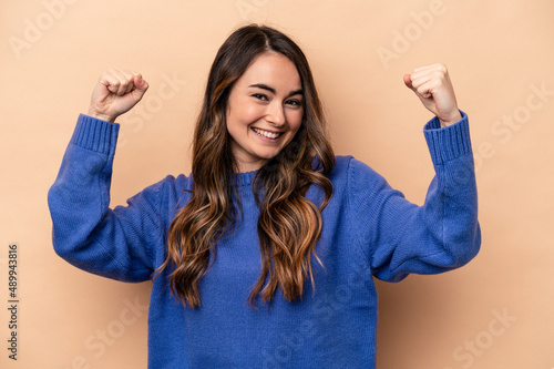 Young caucasian woman isolated on beige background cheering carefree and excited. Victory concept.