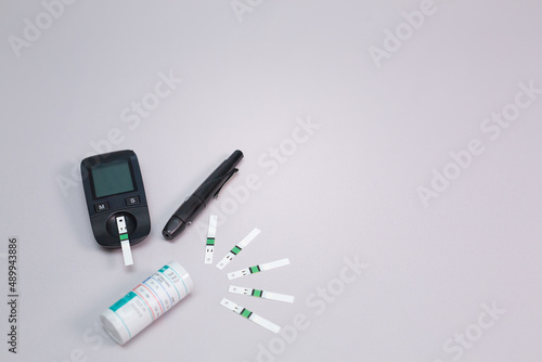 Diabetes equipment, glucose level blood test on blue background with copy space. Diabetic items to control diabetes blood sugar meter, lancet, test strip and lancing device with stethoscope