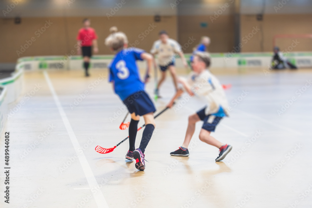 View of floorball match game, court hall indoor venue with junior teenage children school team playing in the background, floor ball hockey match game on arena stadium, copy space
