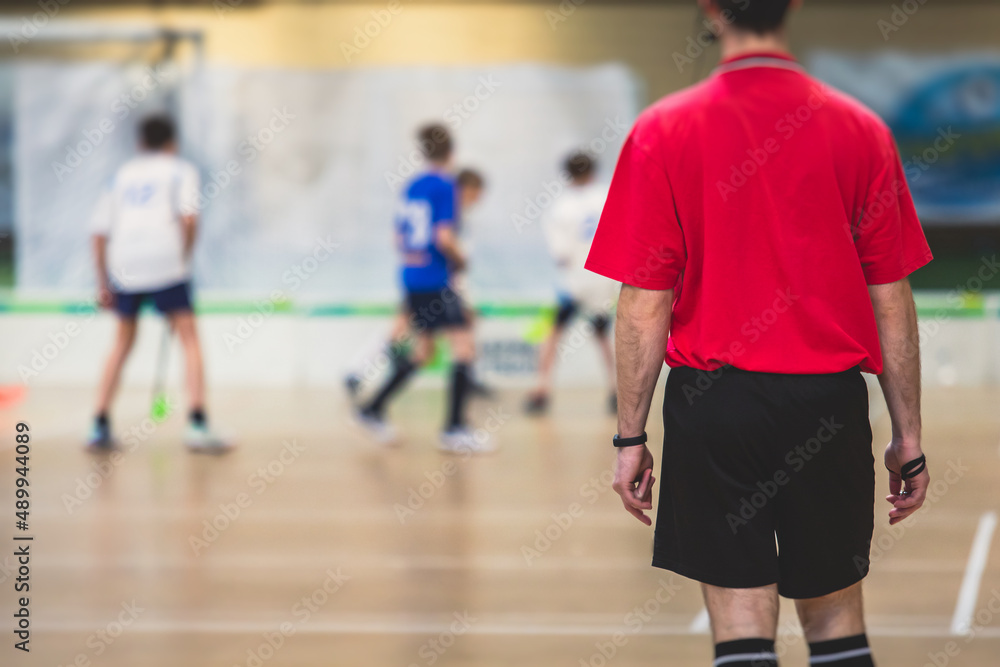 View of floorball match game, court hall indoor venue with junior teenage children school team playing in the background, floor ball hockey match game on arena stadium, copy space