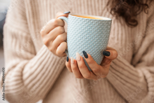 A girl in a beige sweater with a blue mug in her hands. Blue porcelain mug mockup for your design photo