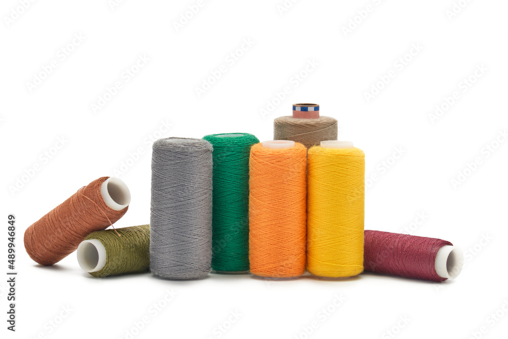 Many spools of thread of different colors scattered on a white background. Many spools of thread of different colors scattered on a white background.