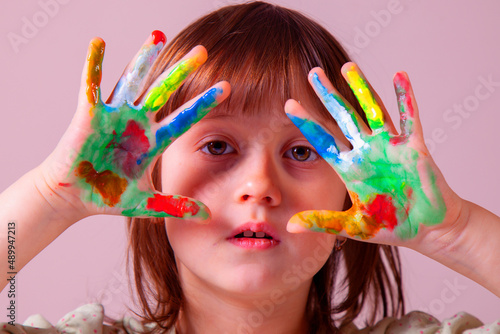 Portrait of beautiful young girl with colorful painted hands. Art and creativity concept