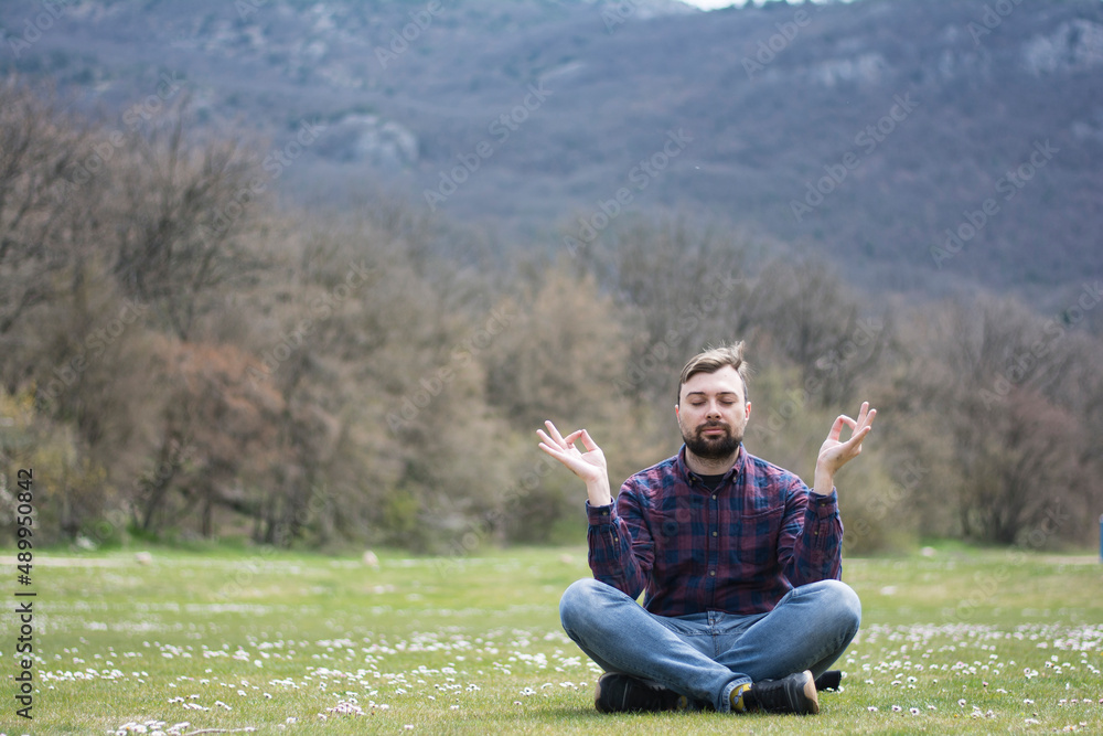 Man in sportswear meditates sitting in a lotus position in nature psychological health in summer Man in sportswear meditates sitting in a lotus position in nature psychological health in summer