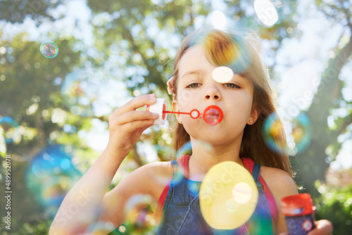 Bubbles and summer vacation. Shot of a cute young girl blowing bubbles outside.