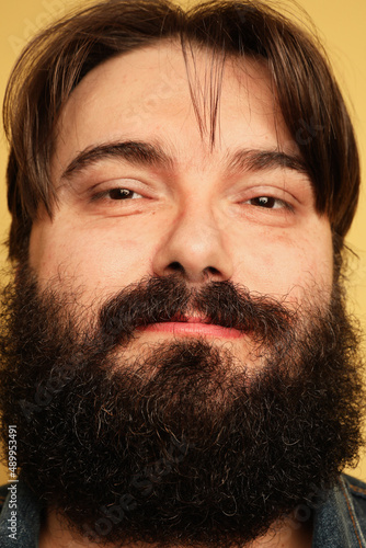 Vertical photo of overweight young man stands on a yellow background.