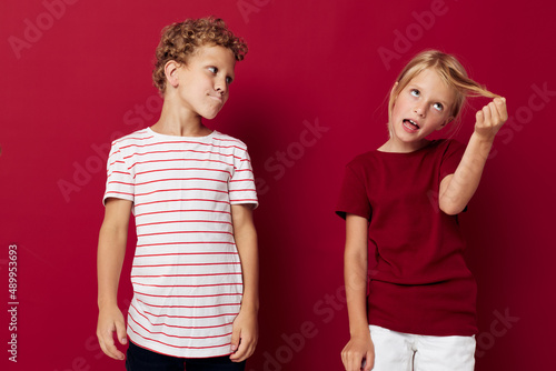 two joyful children emotions stand side by side in everyday clothes on colored background