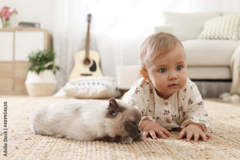Cute little baby with adorable cat on floor at home Cute little baby with adorable cat on floor at home