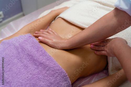 Top view of hands massaging female abdomen.Therapist applying pressure on belly. Woman receiving massage at spa salon