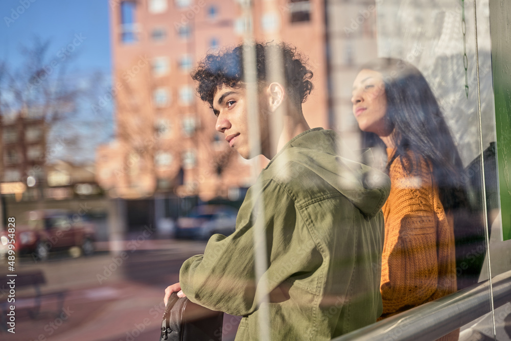 Fototapeta premium Two students while waiting for transport at the bus or tram stop to go to university. concept of sustainable transport.