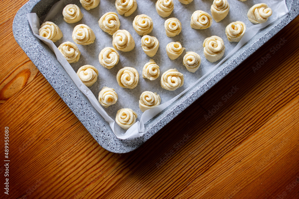 Dough for homemade cookies in a metal baking sheet. Top view. Dough for making homemade cookies. Home cooking baking cookies, buns in the form of roses, snails. The baking sheet is metallic gray. Dough for homemade cookies in a metal baking sheet. Top view. Dough for making homemade cookies. Home cooking baking cookies, buns in the form of roses, snails. The baking sheet is metallic gray.