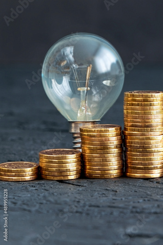 Energy saving. Old bulb.Money coins on a dark background. Energy saving. Stack of coins.Environmental protection