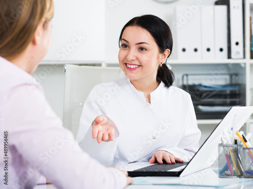 Smiling woman nurse arranging appointment for patient in hospital