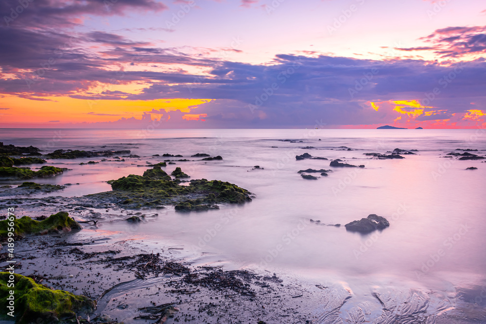 Obraz premium sunset landscape on the beach rocks in foreground