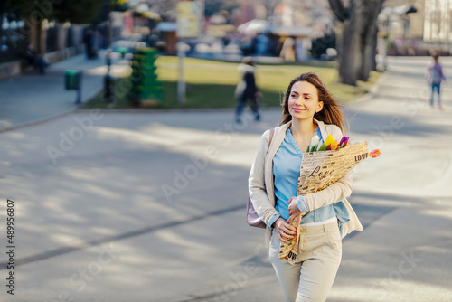 A happy woman carry flowers in a park she got for gift.