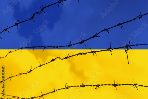 Uprisen view of metal barbed wire fence over Ukraine flag. Stop war. Pray for Ukraine