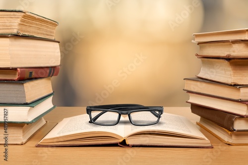 Old books, reading glasses on the wooden desk