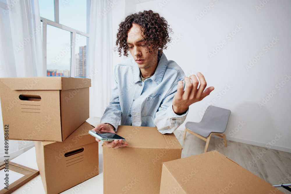 handsome guy cardboard boxes in the room unpacking with phone interior handsome guy cardboard boxes in the room unpacking with phone interior