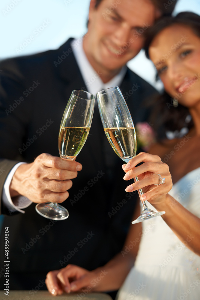 Heres to us. Cropped view of a young bride and groom standing together and toasting their marriage. Heres to us. Cropped view of a young bride and groom standing together and toasting their marriage.