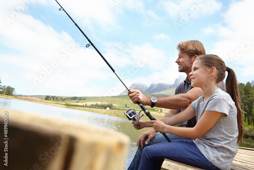 Shes already an expert angler. Shot of a father showing his daughter how to fish.