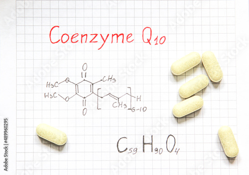Chemical formula of Coenzyme Q10 and some pills on the paper background. Useful vitamin quinone for cells. Close-up. photo