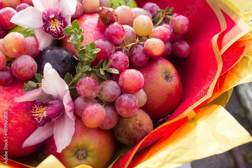 Fruity edible bouquet of red apples with plums, grapes, pomegranate, lime and pink living orchids. High quality photo