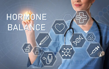 Doctor pointing at virtual screen with inscription Hormone Balance and digital icons on light grey background, closeup
