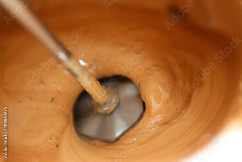 Selective focus of mixing milk, sugar and coffee to make a cappuccino with foam by a handheld milk frother electric mixer for coffee drink, foam bread maker, hand held mixer for mini whisk for latte photo