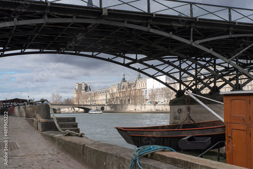 The Seine with boats, under the Pont des Arts in Paris, France, with the Louvre in the distance
