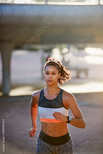 Running with determination. Cropped shot of an attractive young woman taking a run through the city. © Daniel L/peopleimages.com