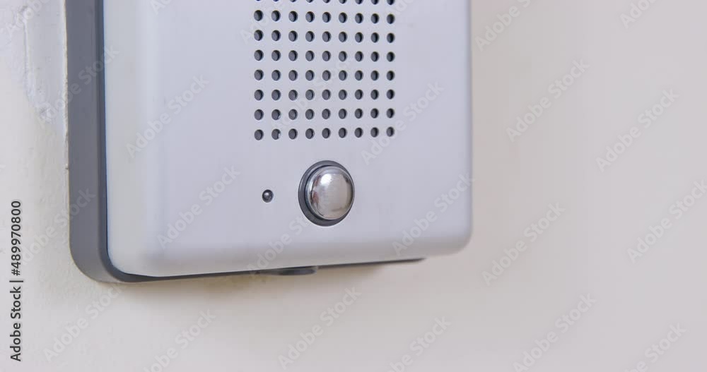 Person presses a doorbell, hanging on white wall, or an intercom call button with his finger, close up. Someone came to visit or to a private institution. Security systems for homes Person presses a doorbell, hanging on white wall, or an intercom call button with his finger, close up. Someone came to visit or to a private institution. Security systems for homes
