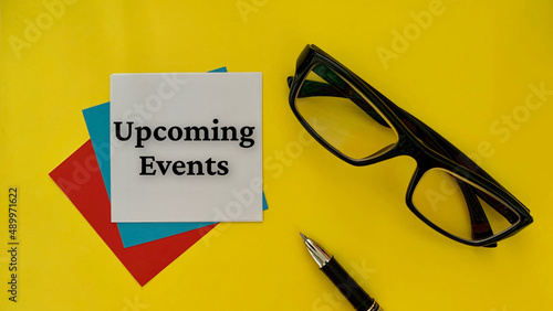 Upcoming events - message on white notepad. With glasses, pen and yellow background. Business concept. photo