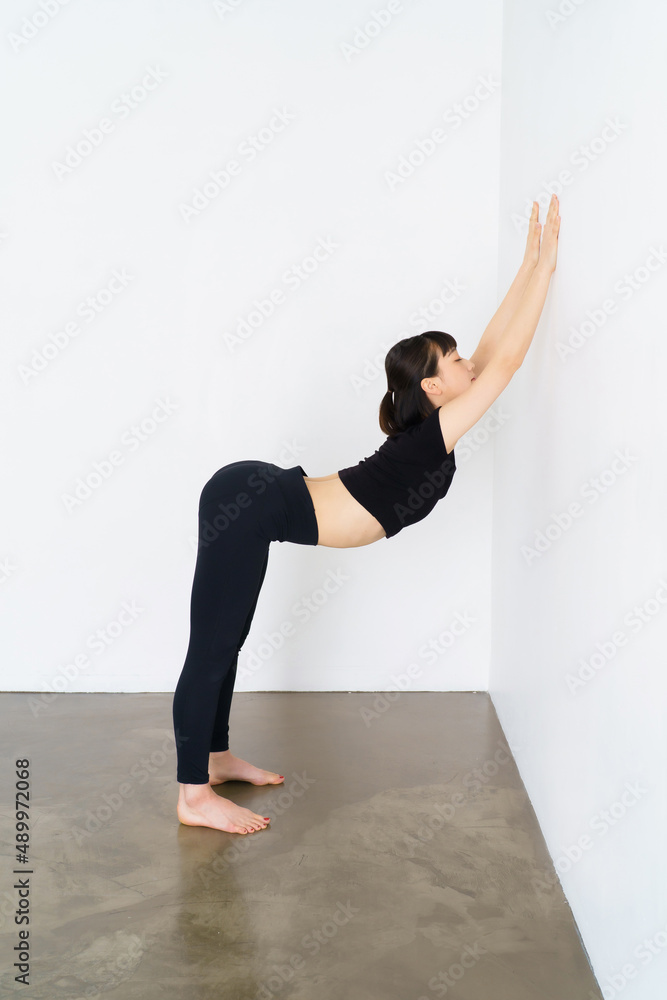壁を使って体操をする女性