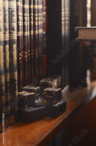 Holy Jewish items on a bookshelf in a library, tefillin, Jewish phylacteries, old leather-bound Jewish books/seforim
