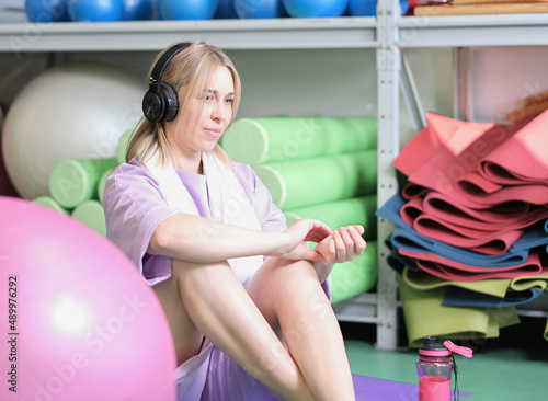 blond woman checking pulse after training in a gym. cardio workout. fitness indoors.