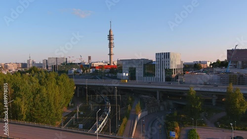 Helsinki.Finland-August 30.2021: Beautiful aerial shot of a train driving through the downtown of Helsinki. City transport. Awesome cityscape. Cars driving by. Drone slowly moving backwards. photo