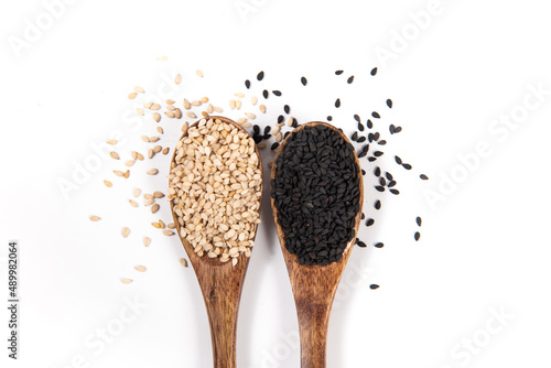 White sesame and black sesame seeds in spoon on white background