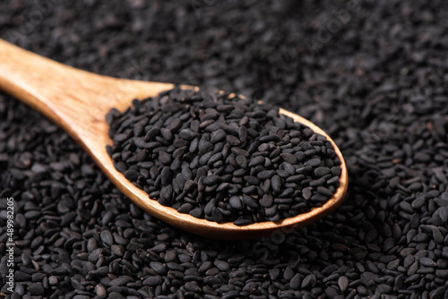 Canvastavla Close-up black sesame seeds in wooden spoon on black sesame seed background
