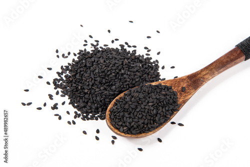 black sesame seeds in spoon on white background