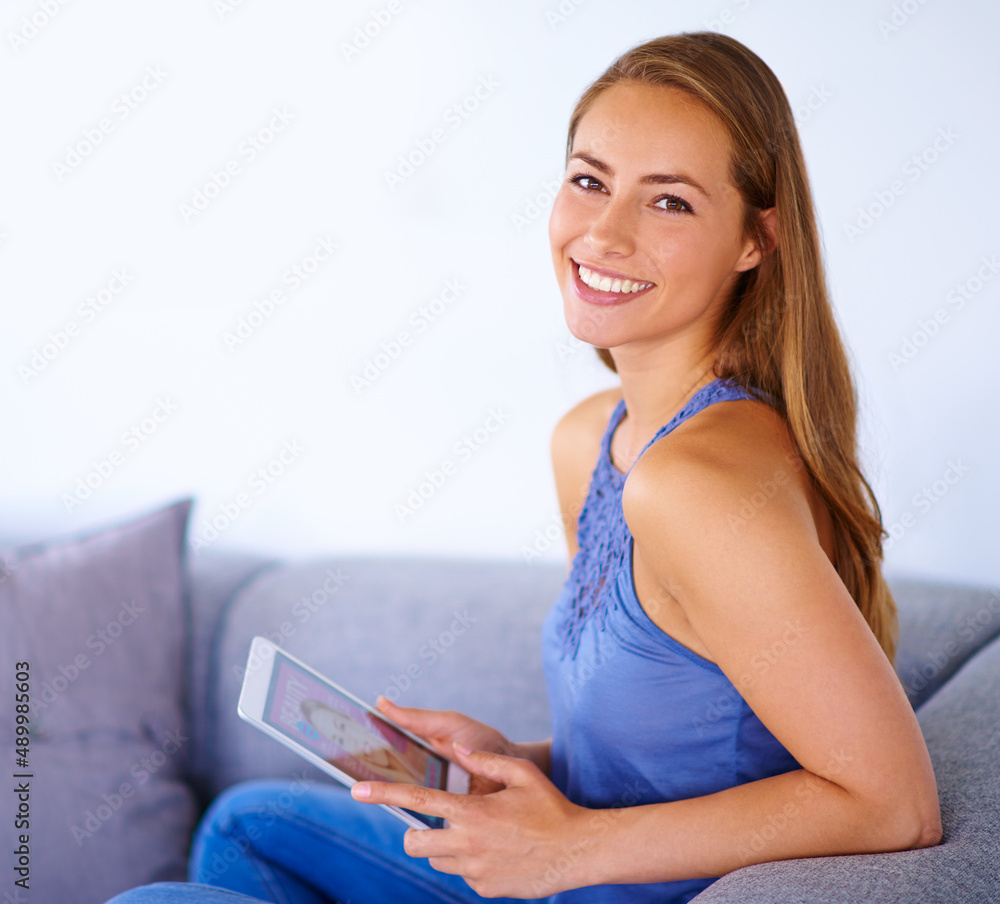 Naklejka premium Making the most of the weekend. Shot of a young woman using a digital tablet at home.