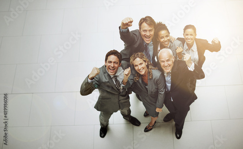 We made it. High angle portrait of a group of businesspeople cheering in the office lobby.
